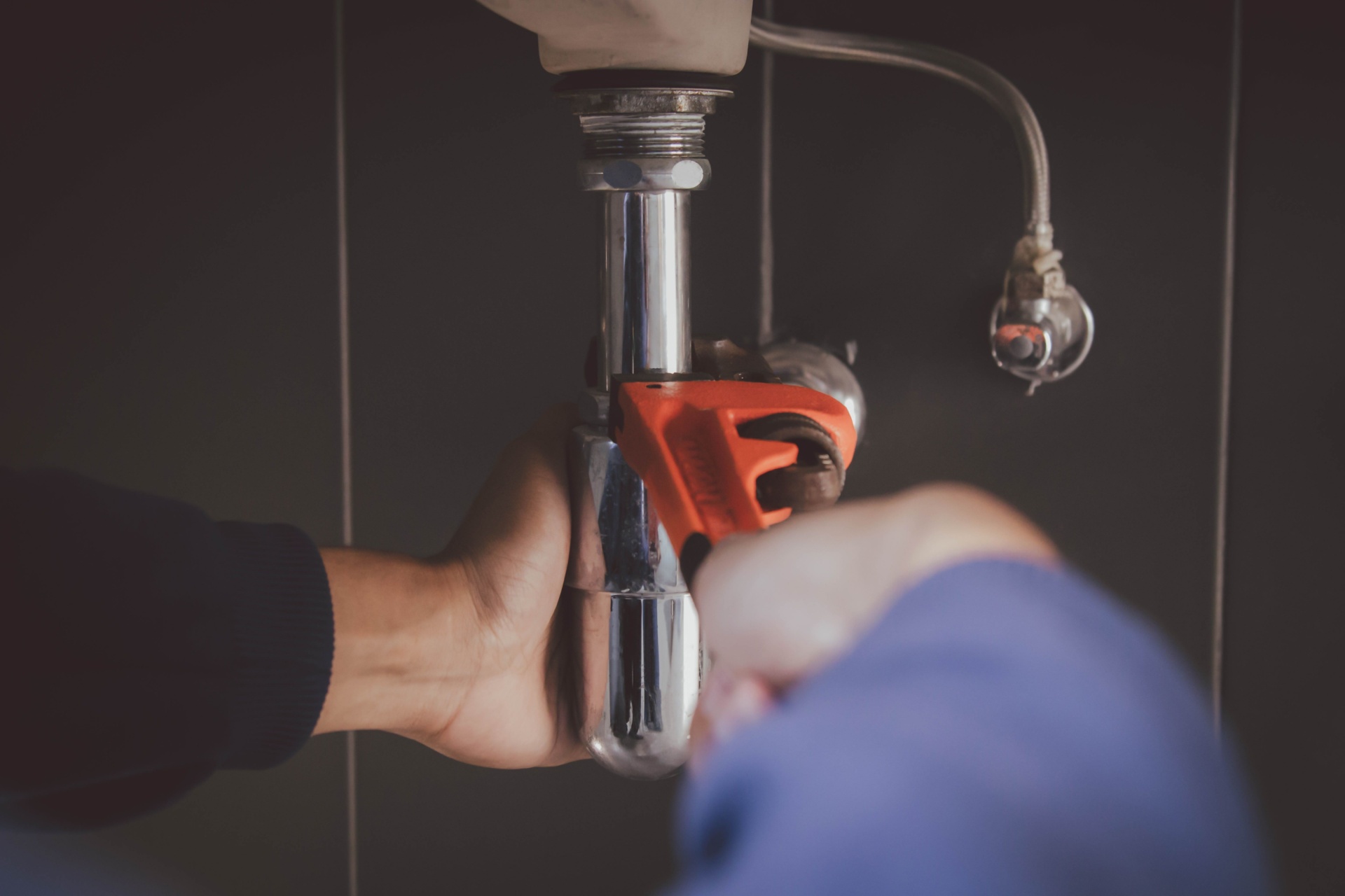 Rørlegger står med skiftenøkkel og skal skru til på rør til en vask